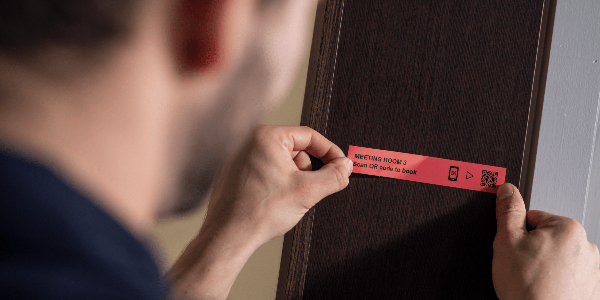 A man placing a barcode label on a computer. 