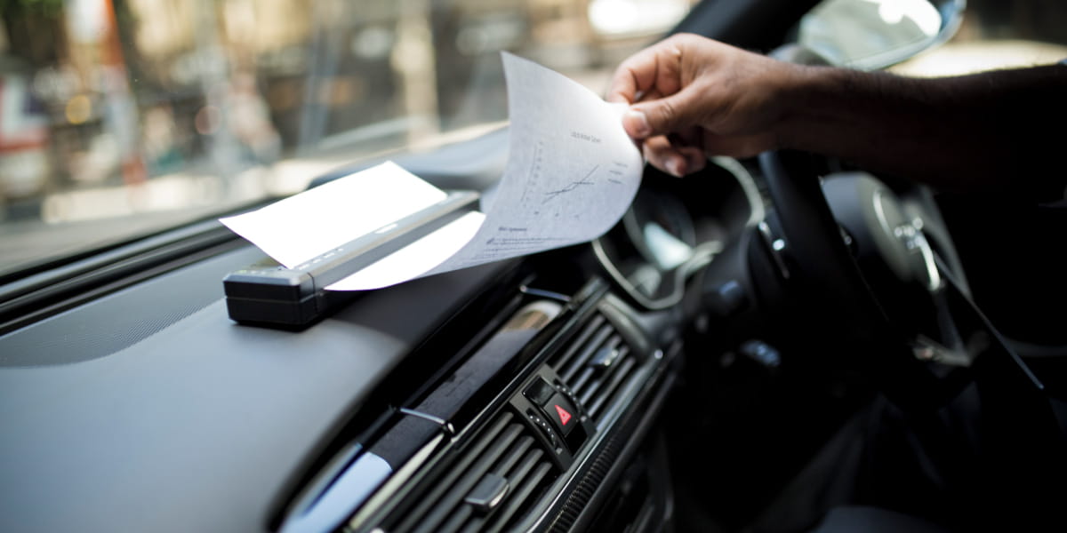 A Brother portable A4 document printer printing from a car