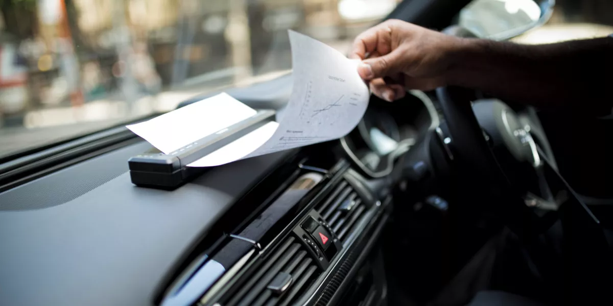 A Brother portable A4 document printer printing from a car