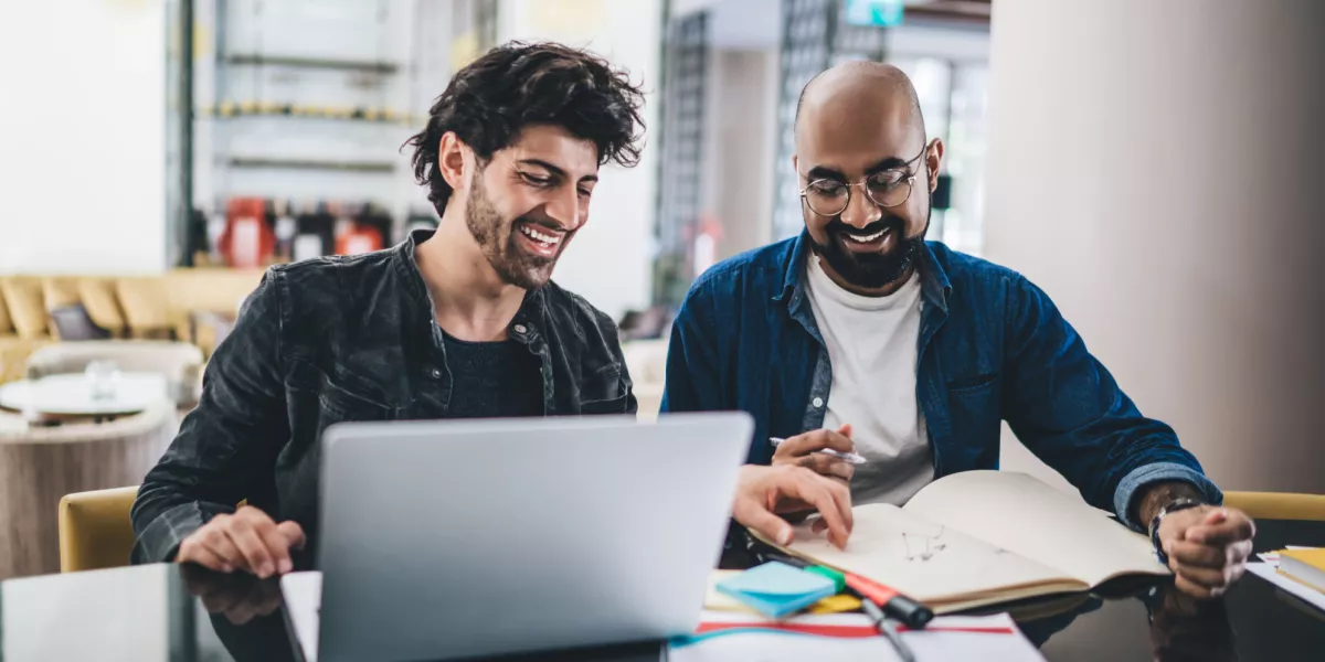 Two businessmen sitting and talking in front of a laptop