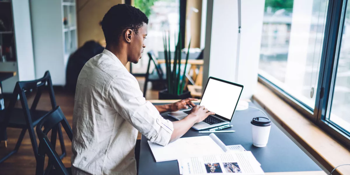 A male ecommerce business owner working on a laptop with a coffee.