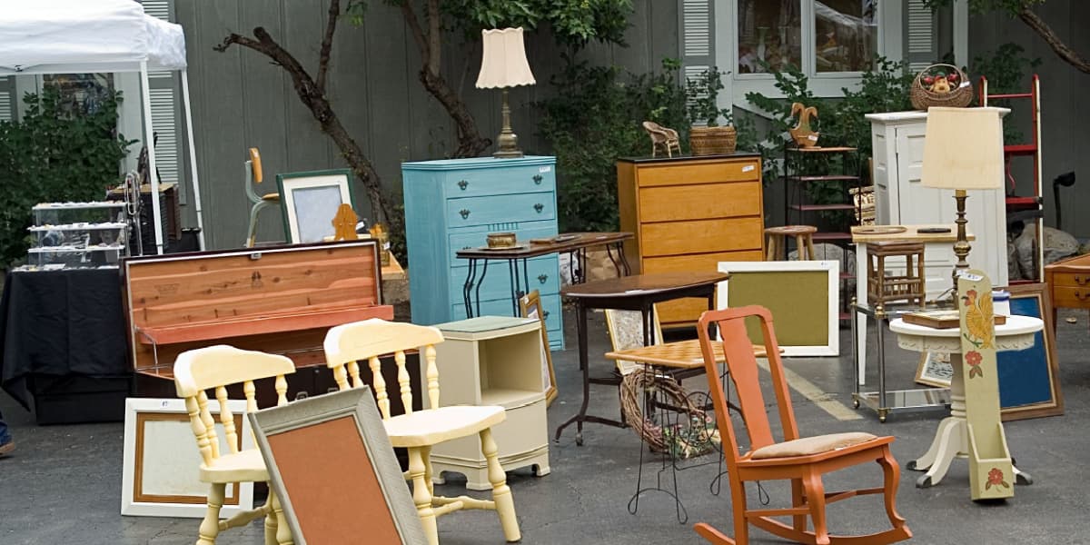 Multiple antique chairs and drawers out the front of a second hand store