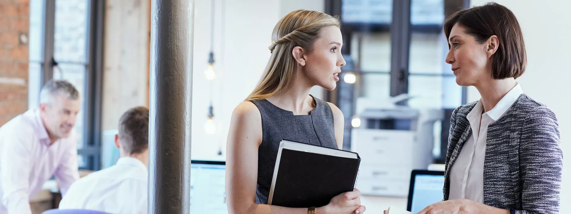 An office environment with two employees talking in a boardroom