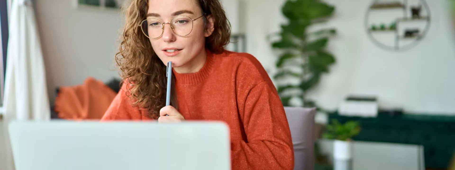 Young lady working from home in front of a laptop learning something new