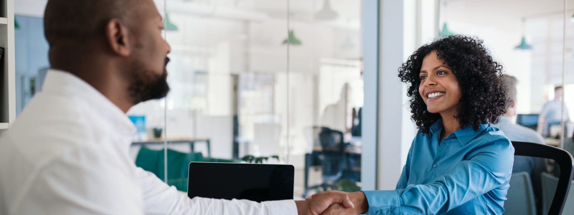 A human resources manager shaking hands with a recruit in an office environment
