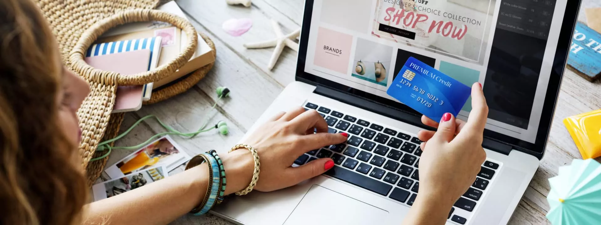 A woman with a credit card in front of a laptop shopping online