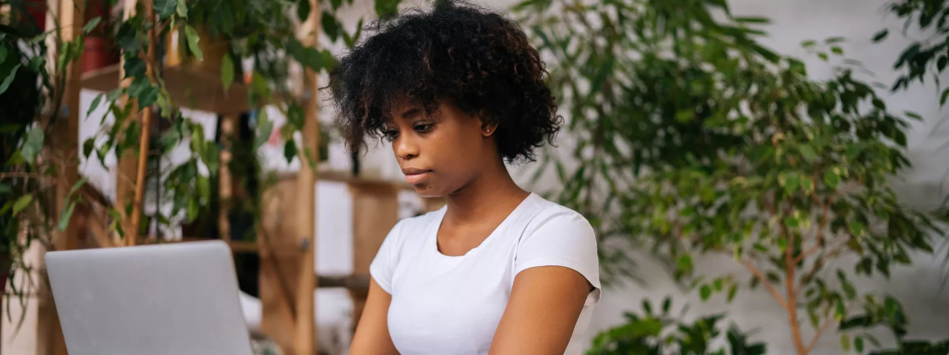 A lady working from home with lots of plants and greenery visible depicting biophilic design
