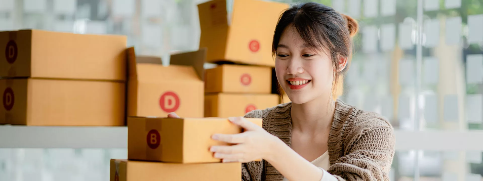 Female eCommerce owner stacking packages on a desk.