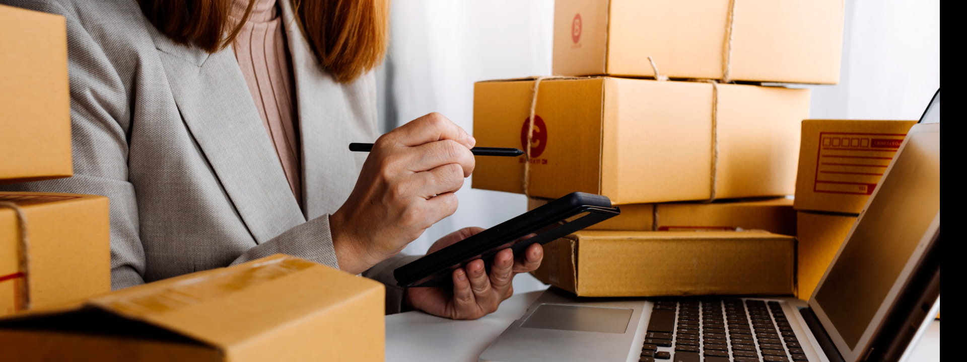 A female eCommerce business owner with packages and a laptop on her phone