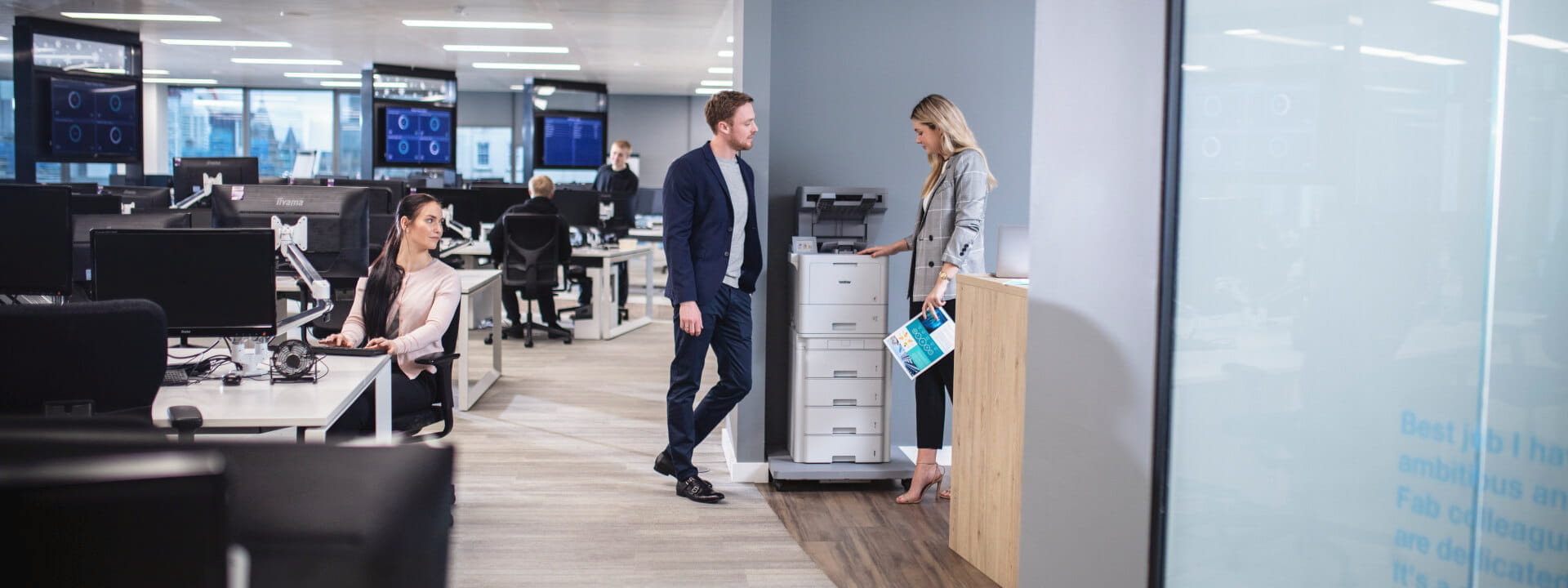 Two professionals in an office next to a Brother Colour Laser Printer using NFC technology