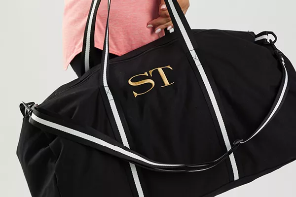 image of a person carrying a monogramed sports bag