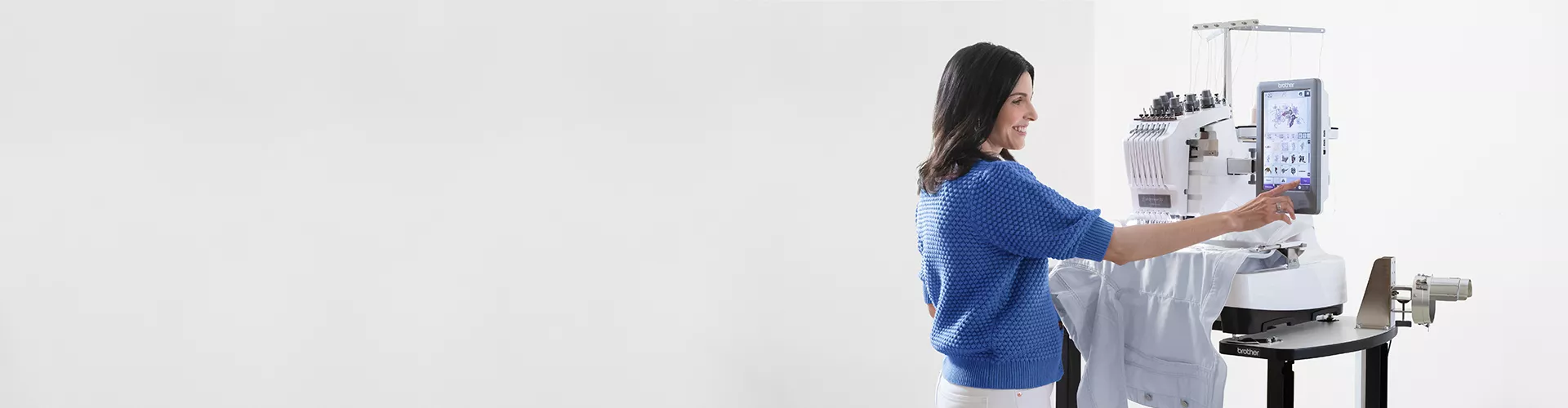 Image of a person standing in front of a PR Multi-needle Embroidery machine utalising the touch screen interface