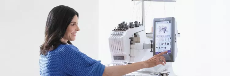 Image of a person standing in front of a Brother Multi-needle embroidery machine interacting with the large touch screen interface