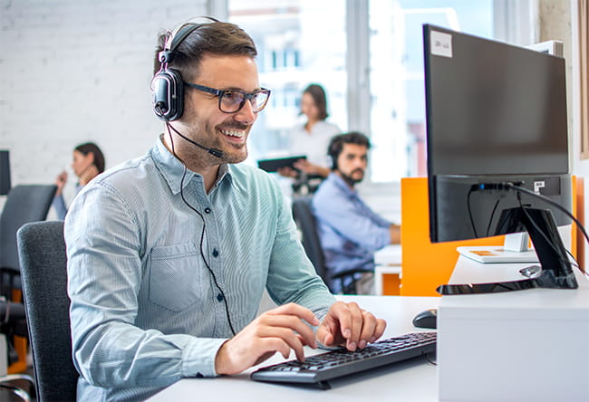 man talking on the headset whilst typing on the computer