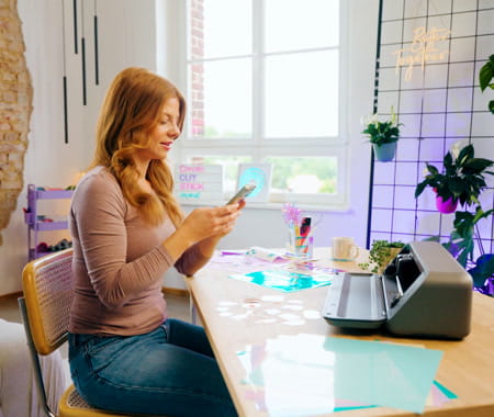 Person sewing at a Brother machine beside a smartphone displaying Brother online support.