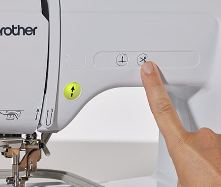 image of a person activating the automatic tread cutter function on a Brother Innov-is M330E Embroidery machine