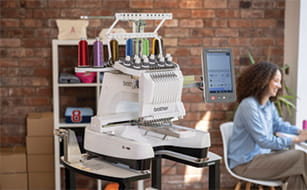 Image of a lady with a Brother PR1060W embroidery machine in the background