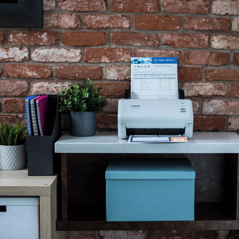 ADS-3100 sitting on a desk with  paper in the feeder and tray