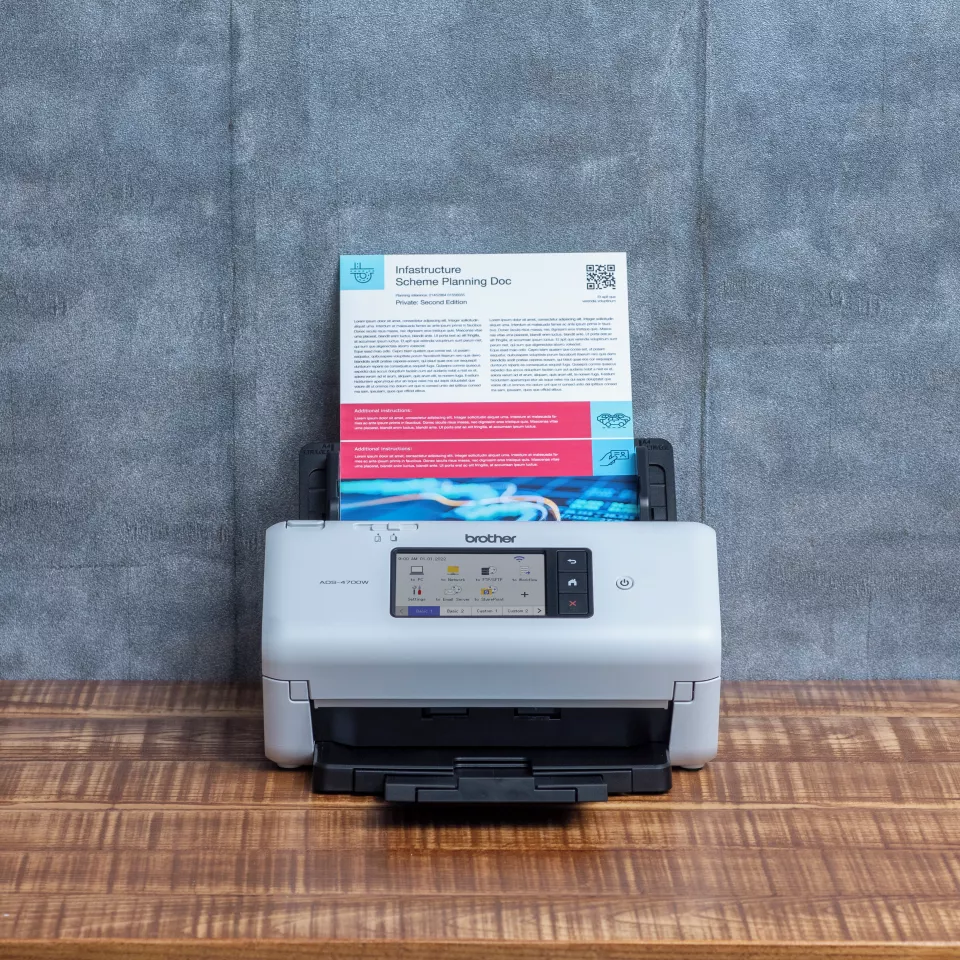 ADS-4700W sitting on a table with paper in the feeder facing forward