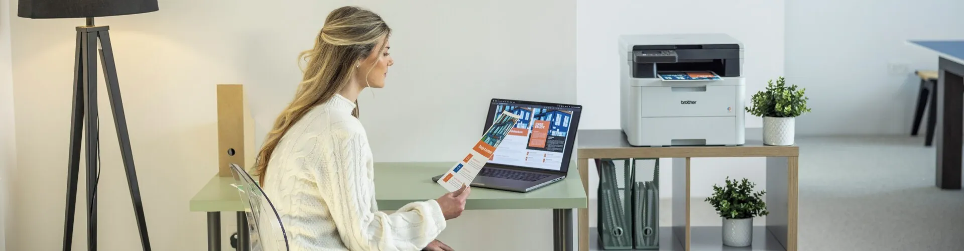 woman working on her laptop with a brother printer printing in the background