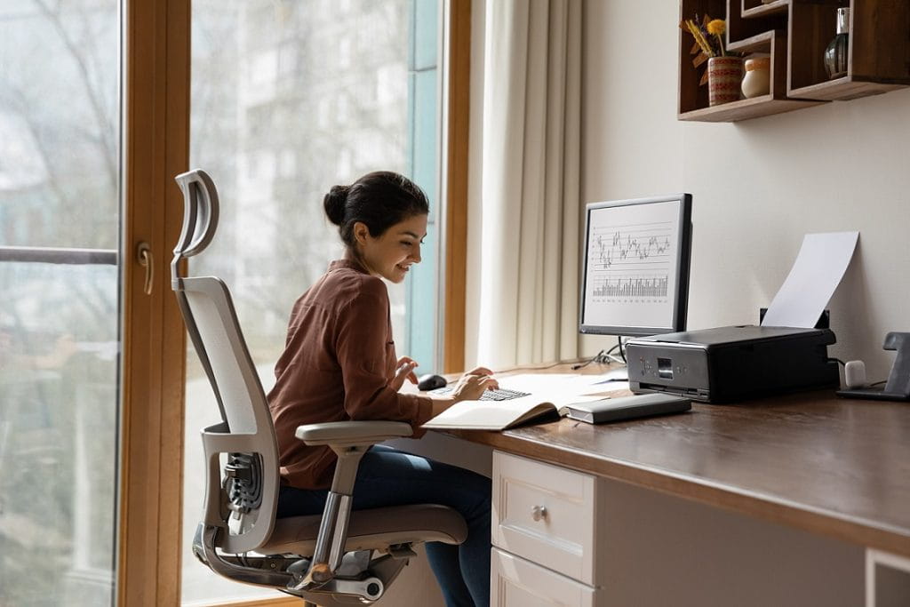 A young woman sitting while concentrating on her paperworks showing good ergonomics