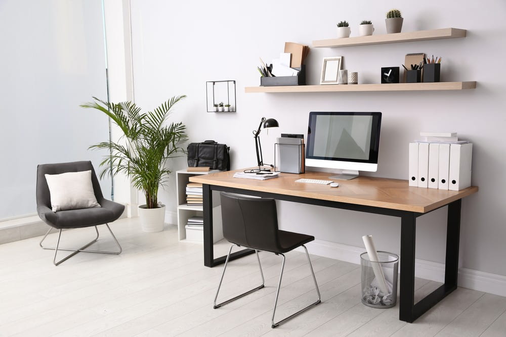 A modern home desk in a home office with chair and screen and other items.