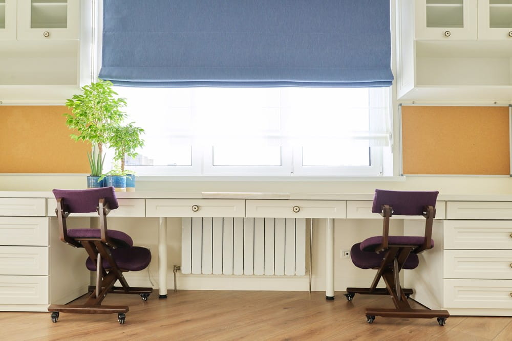An empty home workspace for two people with natural light beaming through a window.