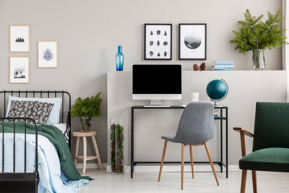 A modern bedroom home office with a desk, chair and artwork on the wall.