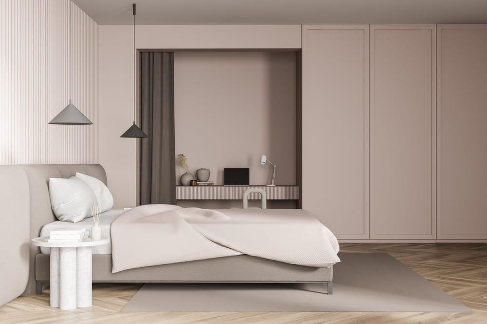 A modern bedroom home office with a built-in desk with chair and laptop.