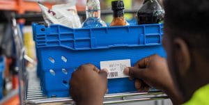 Hands placing a label with a barcode on goods inside a warehouse.