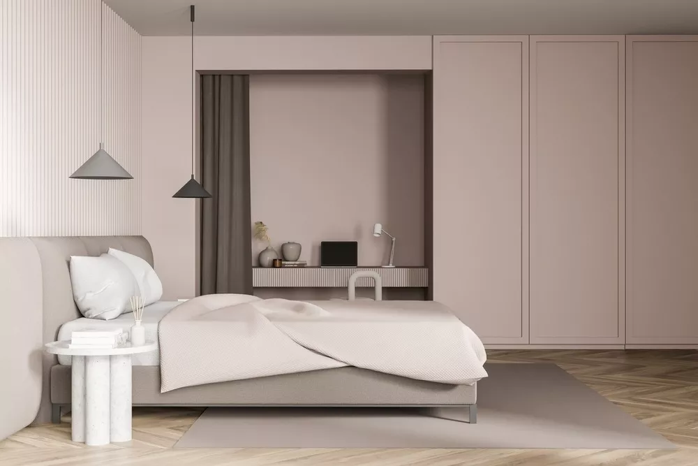 A modern bedroom home office with a built-in desk with chair and laptop.