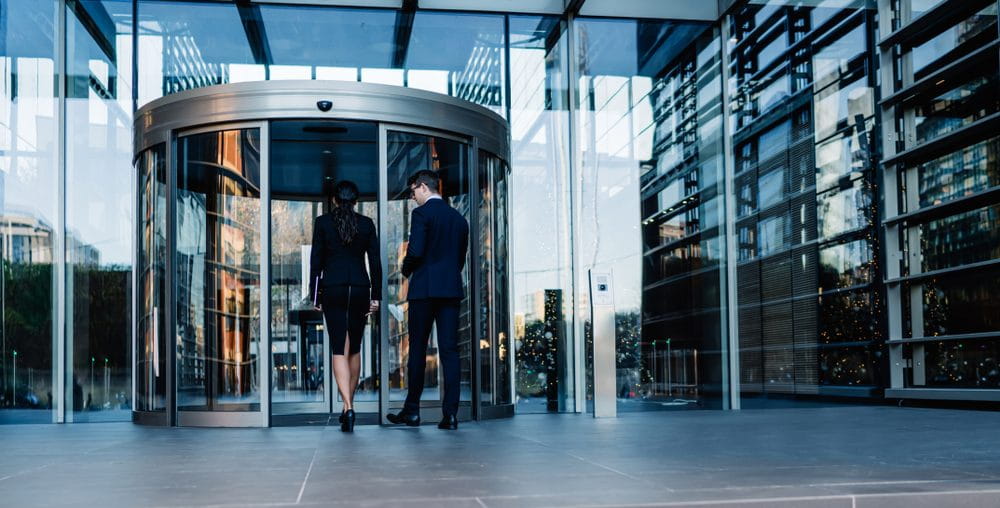 Two male and female professionals walking into an office building.