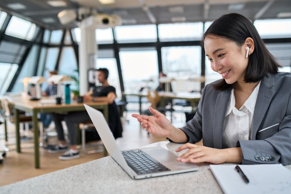 Young businesswoman working on a laptop in a modern office setting. 